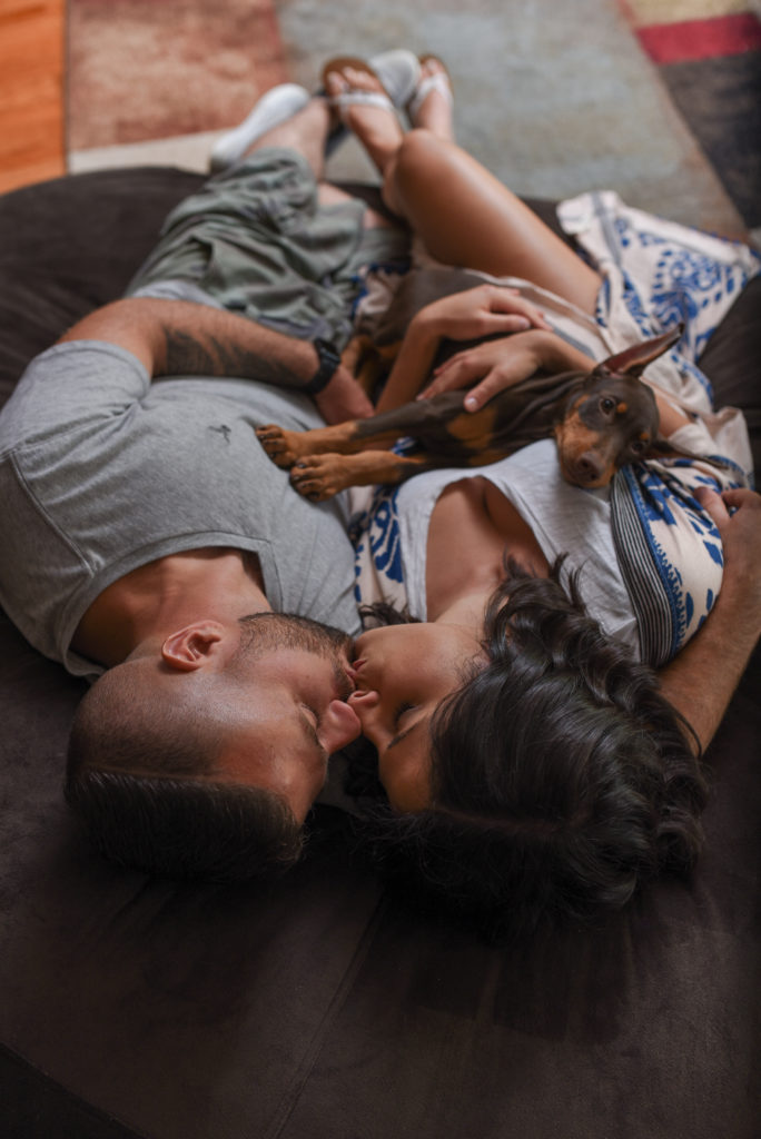 Location of engagement session matters.Couple snuggling on their love sac with their puppy