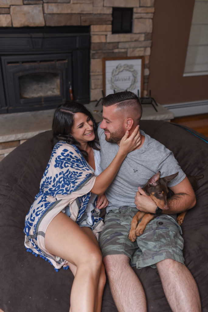 Location of engagement session matters.Couple snuggling on their love sac with their puppy