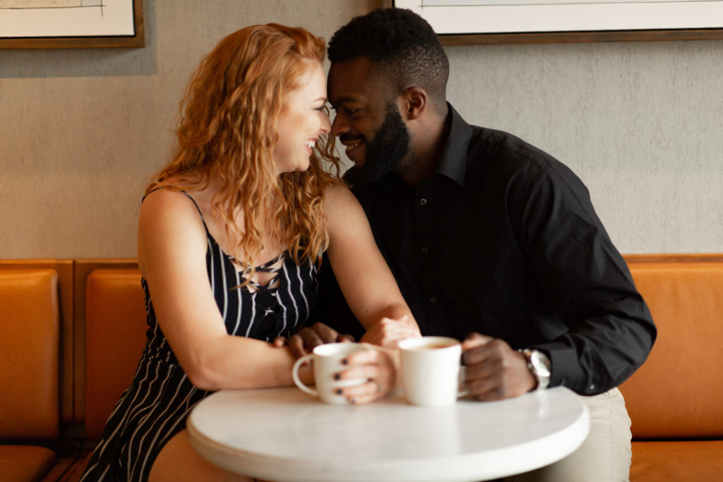 Stunning interracial couple enjoying lattes and one another at Starbucks
